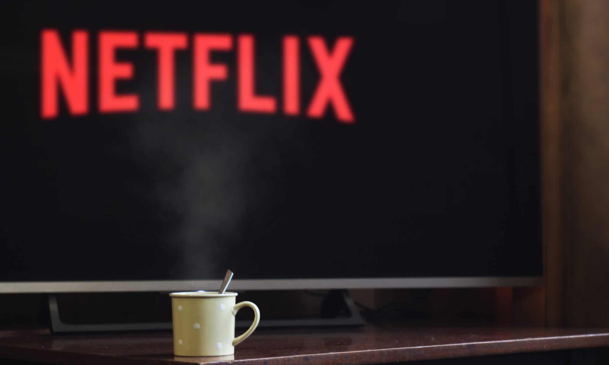 A mug sitting in front of a TV that is showing the Netflix logo