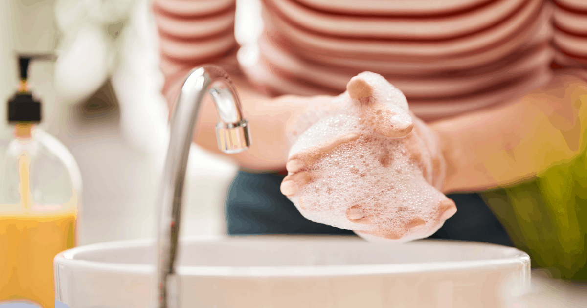 A woman in a red and white striped shirt washing her hands.
